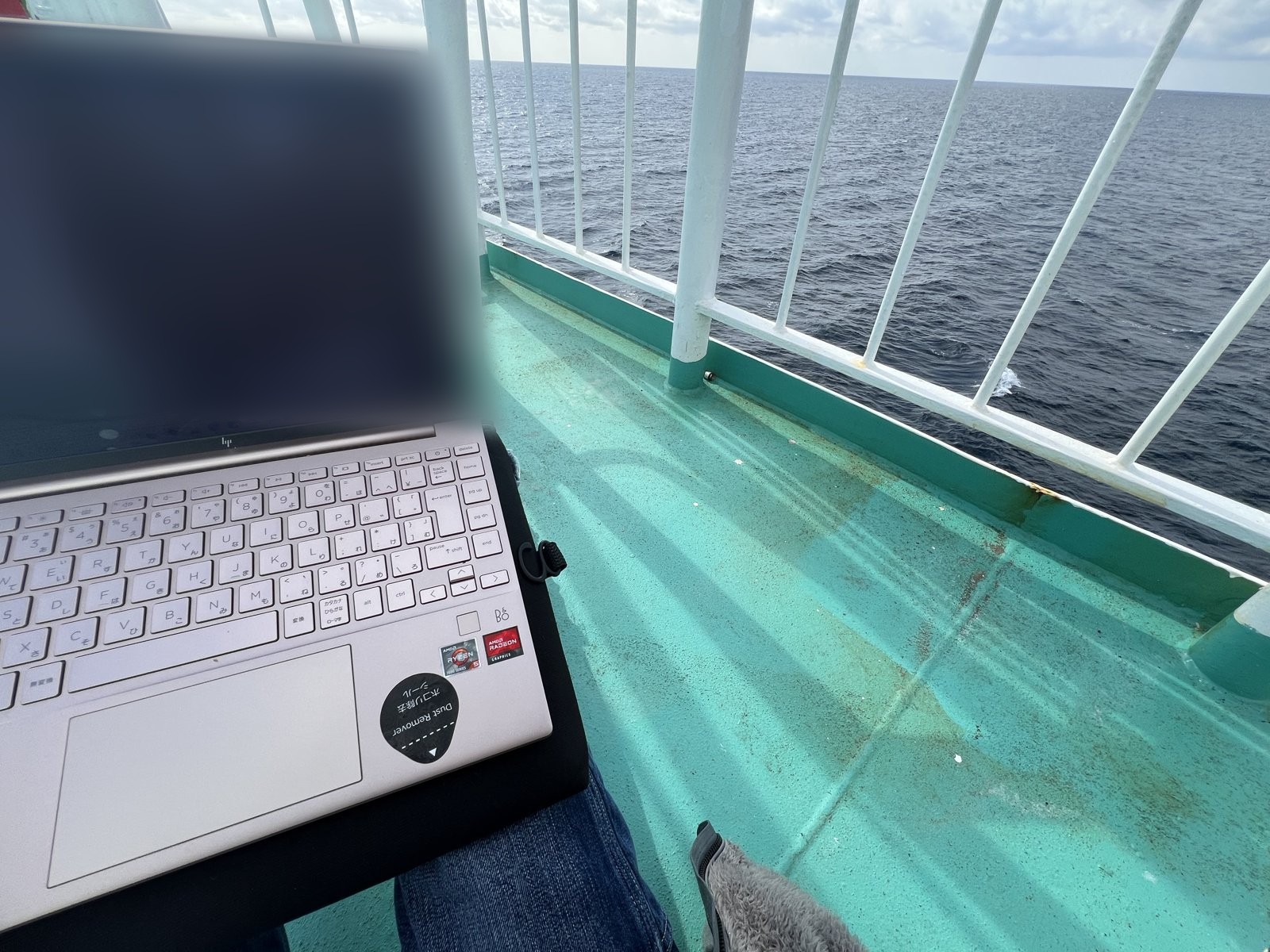 膝の上のPCと、その向こうの海